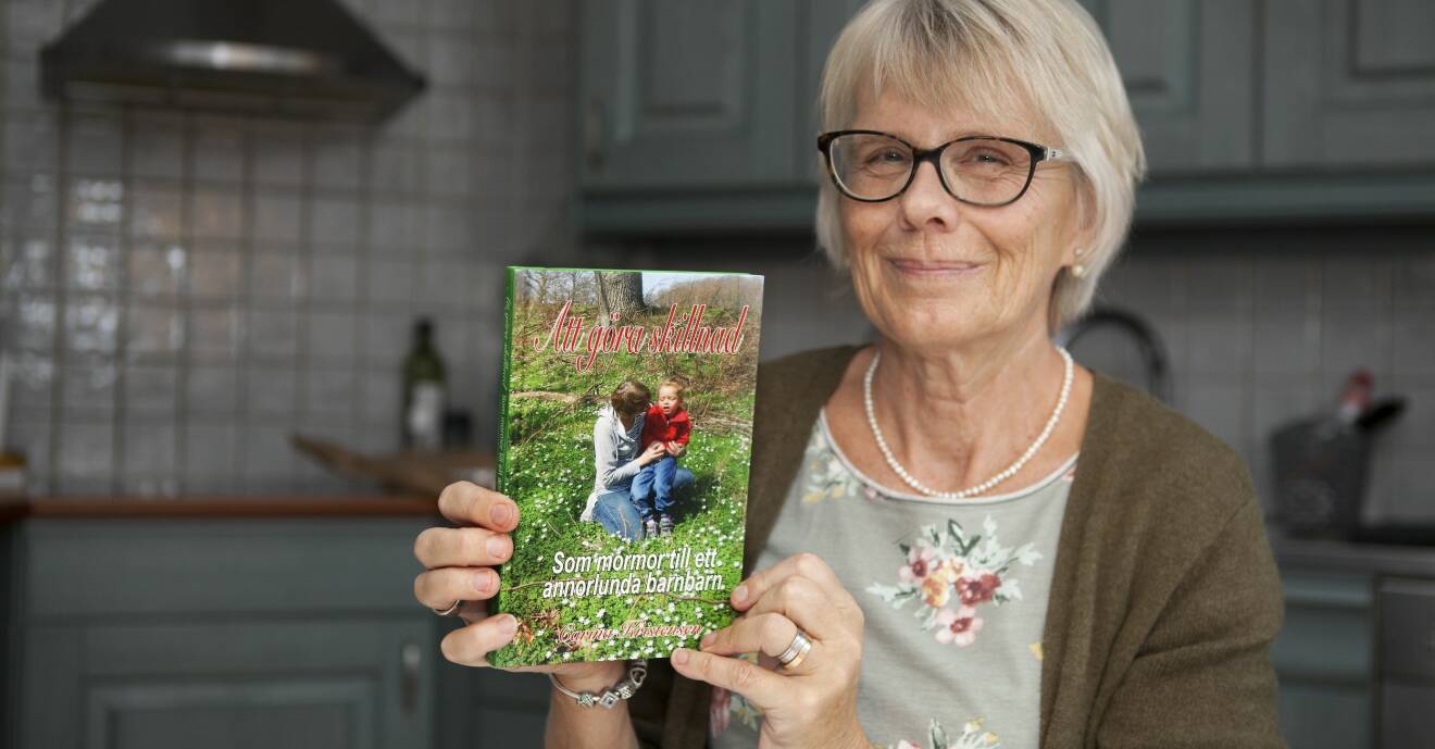 Carina visar upp omslaget till sin bok Att göra skillnad - som mormor till ett annorlunda barnbarn.