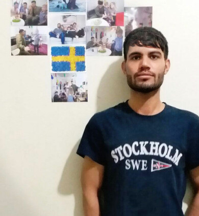 På väggen i rummet han hyr i Iran, har Sha tejpat upp bilder från sin tid i Sverige. Foto: Privat Sha Mohammadi framför bilder från sin tid i Sverige.