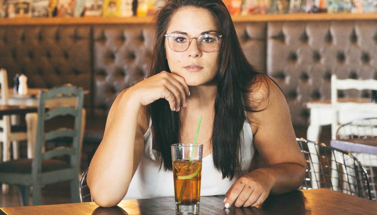 Kvinna sitter på ett kafé och dricker iste.