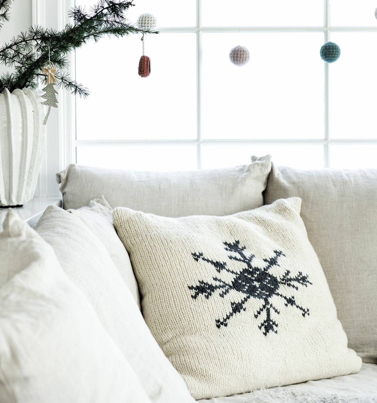 Kudde med broderat mönster av snöflinga i soffa.