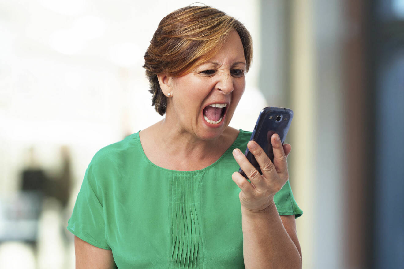 Arg kvinna skriker på sin telefon.