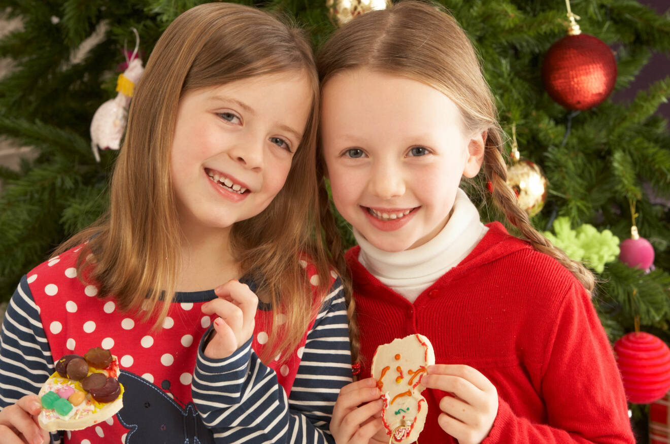 Två systrar, sju år, framför julgranen.