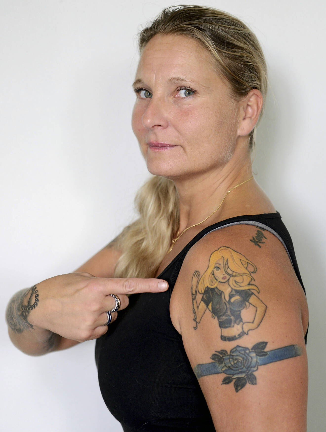 Polisen Jenny, som misshandlades av sin partner, pekar på en tatuering av en stark kvinna.