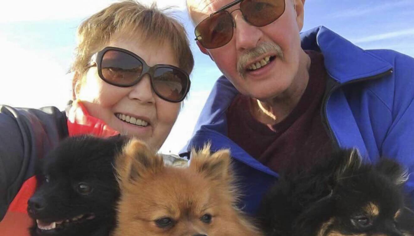 Ett äldre glatt och friskt par utomhus med sina hundar.