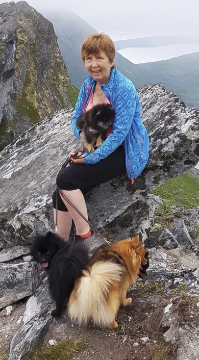 Nu kan Venke gå promenader igen och styrketräna tre gånger i veckan. Foto: Privat Venke sitter på en bergsklippa med sina tre hundar.