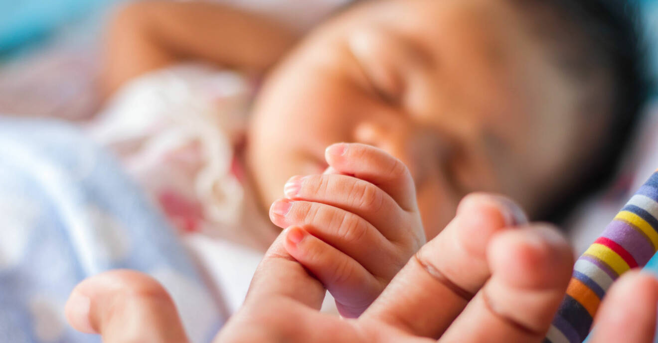 Nyfödd bebis håller i sin mammas finger.