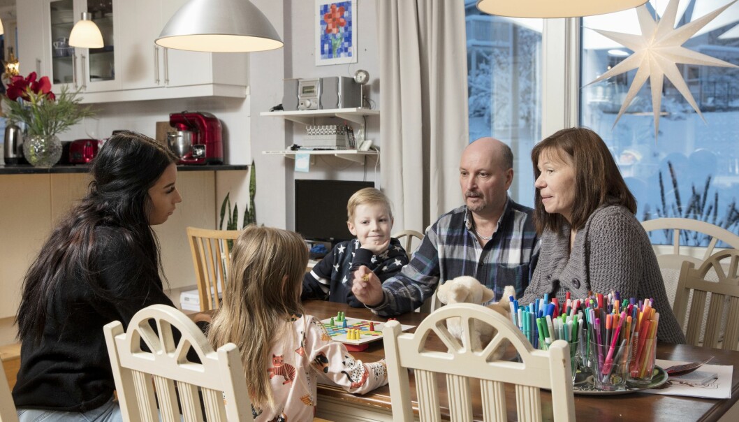Jerry och Annica är familjehem, men även jourhem under julen. Här spelar de spel med Matilda, Lovisa och Isak. Matilda, Lovisa, Isak, Jerry och Annica spelar fia med knuff vid köksbordet och fönstret bakom dem hänger en adventsstjärna.