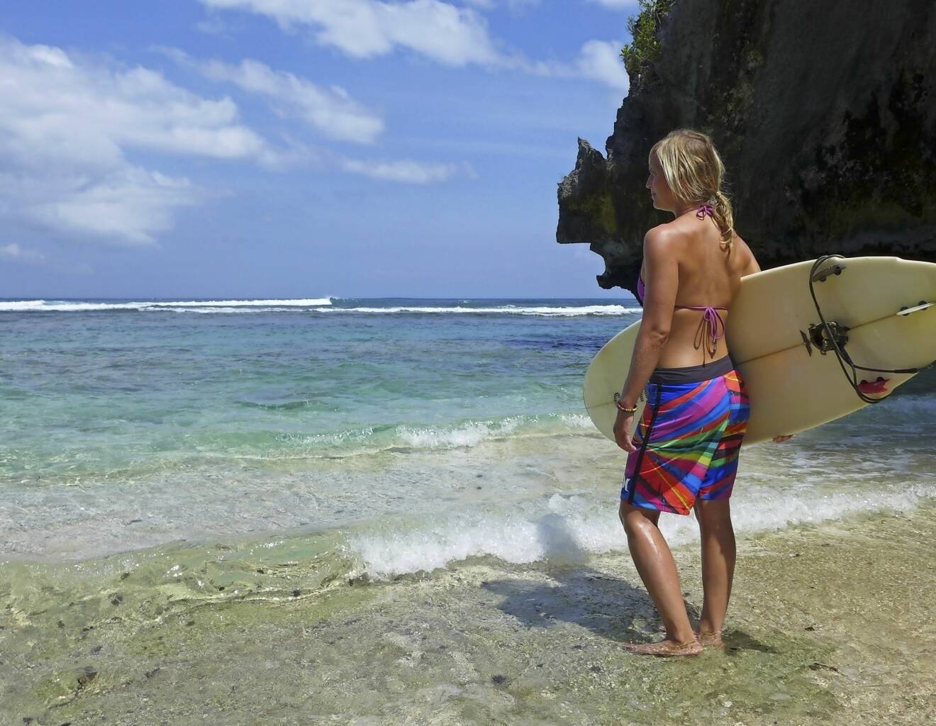 Johanna, som lever som modern nomad, med surfingbräda på en strand i Portugal.
