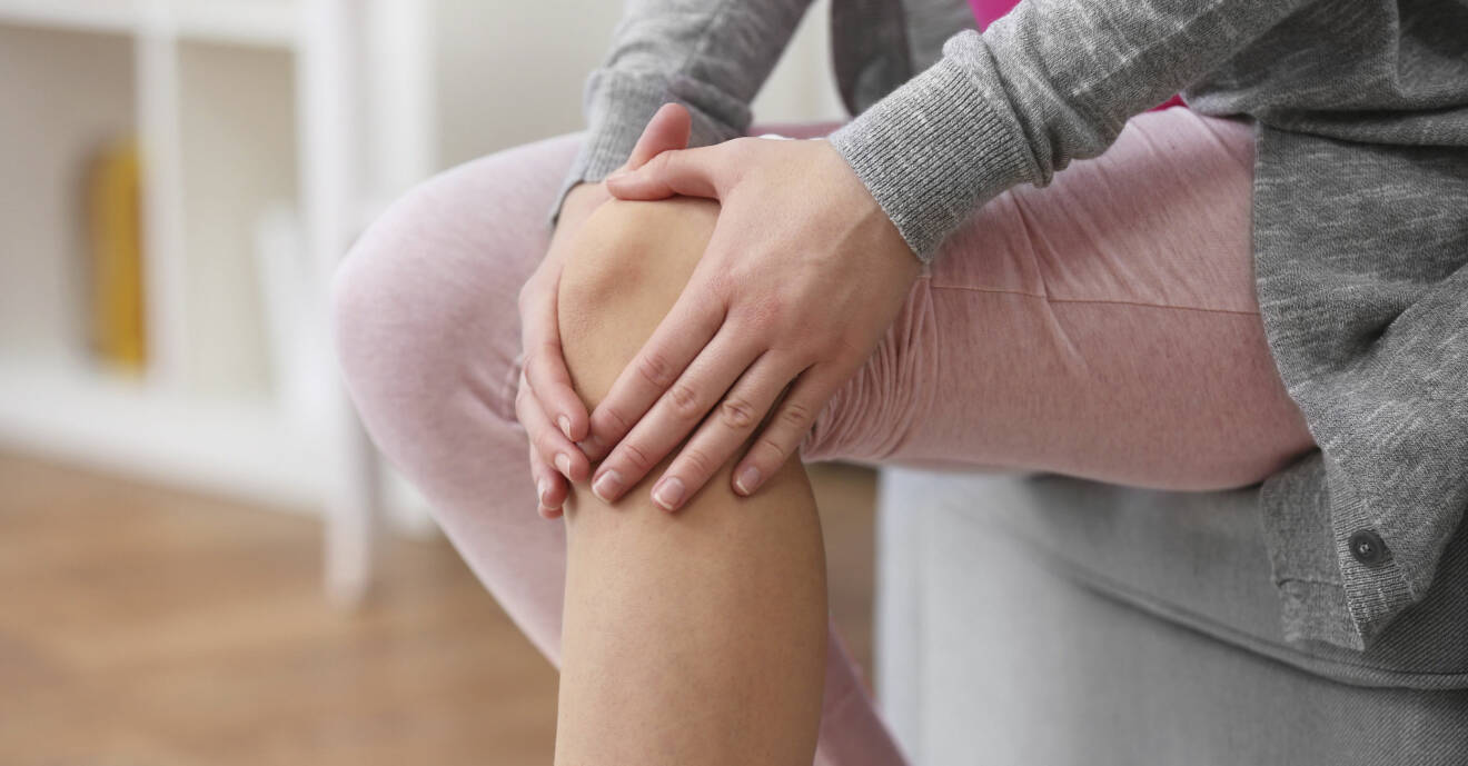 Kvinna med artrossmärta håller sig om sitt knä.