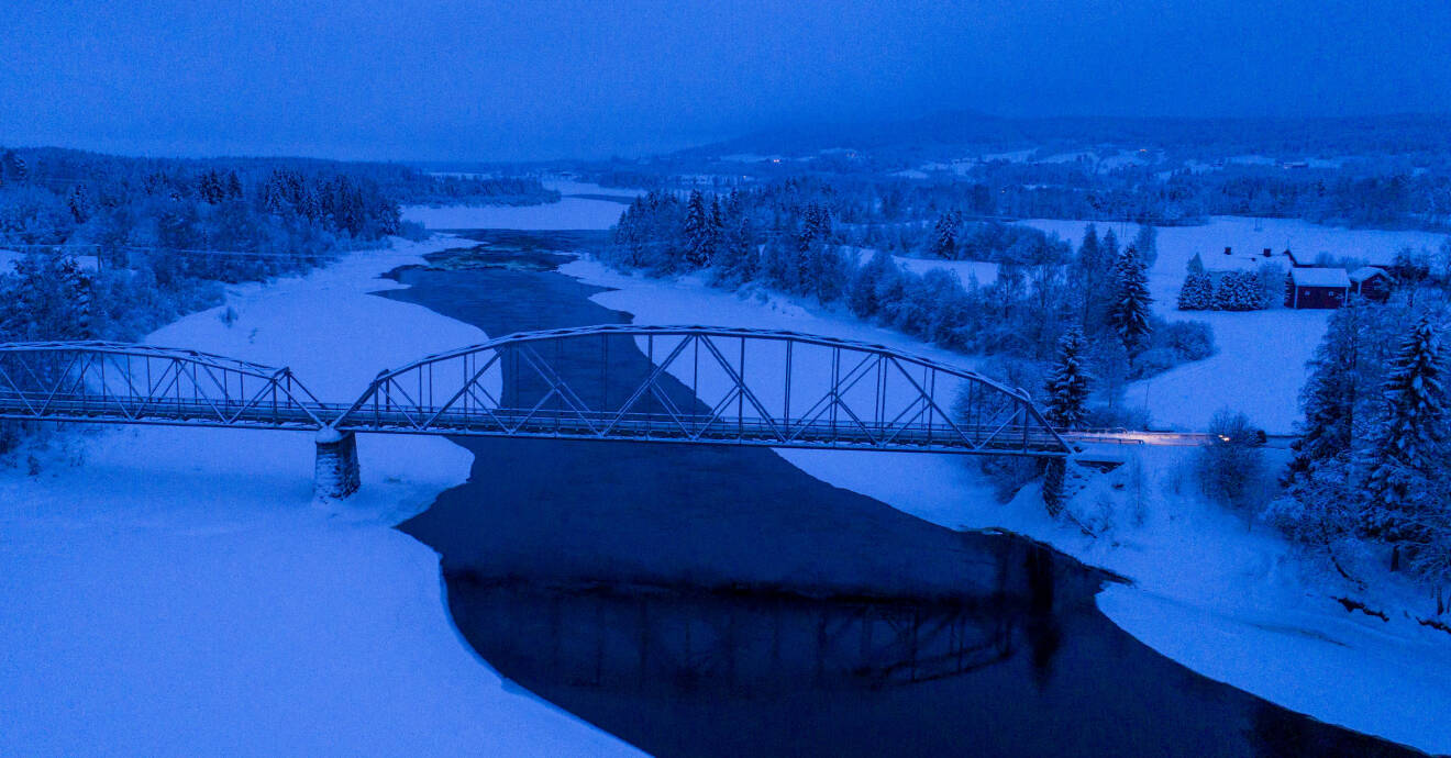 Älv med bro över i snölandskap