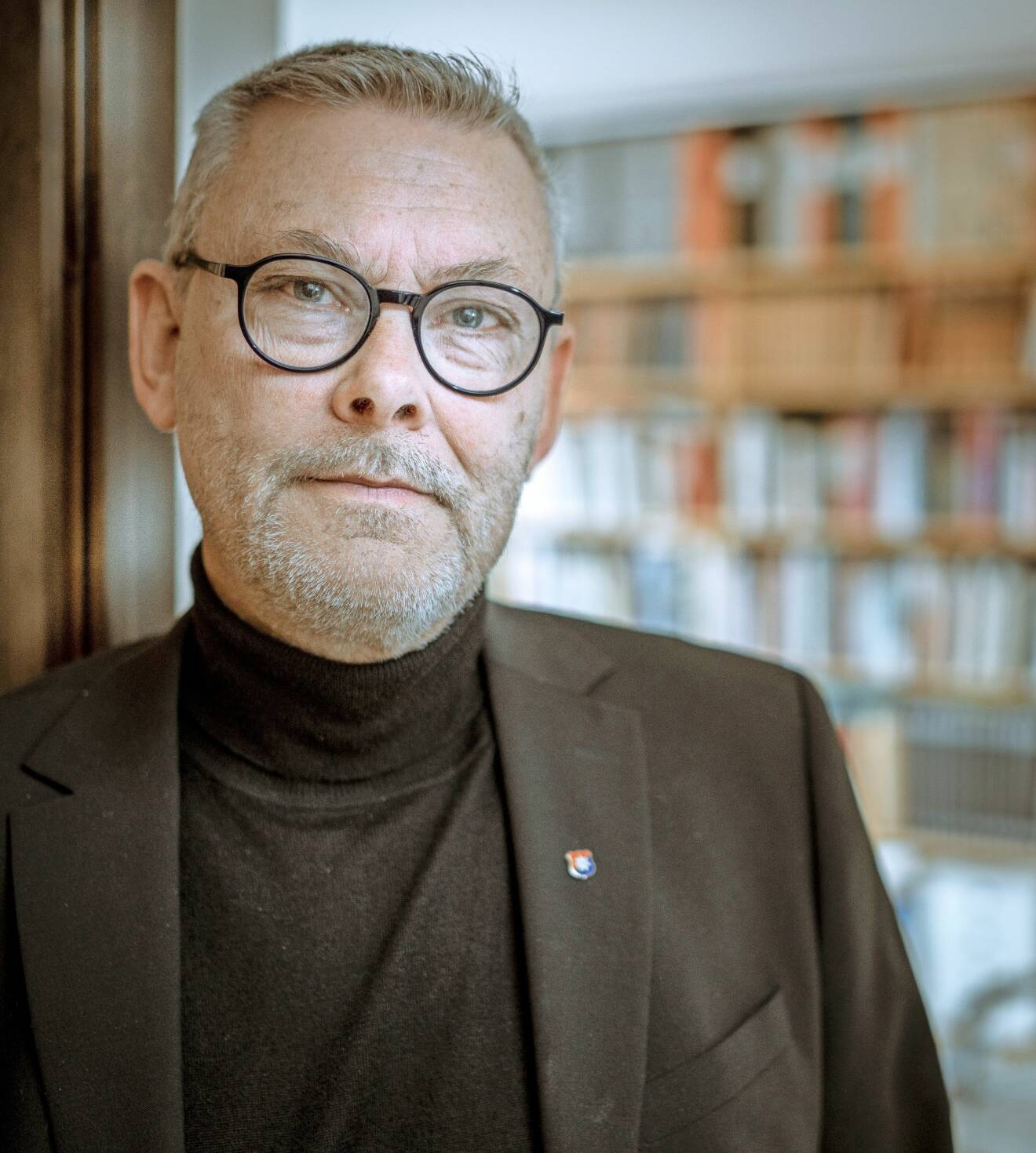 Författaren Lars-Åke Skagegård står framför en bokhylla och berättar om hur det var att skriva en bok om kärlekshistorien mellan Gunilla von Post och John F Kennedy.