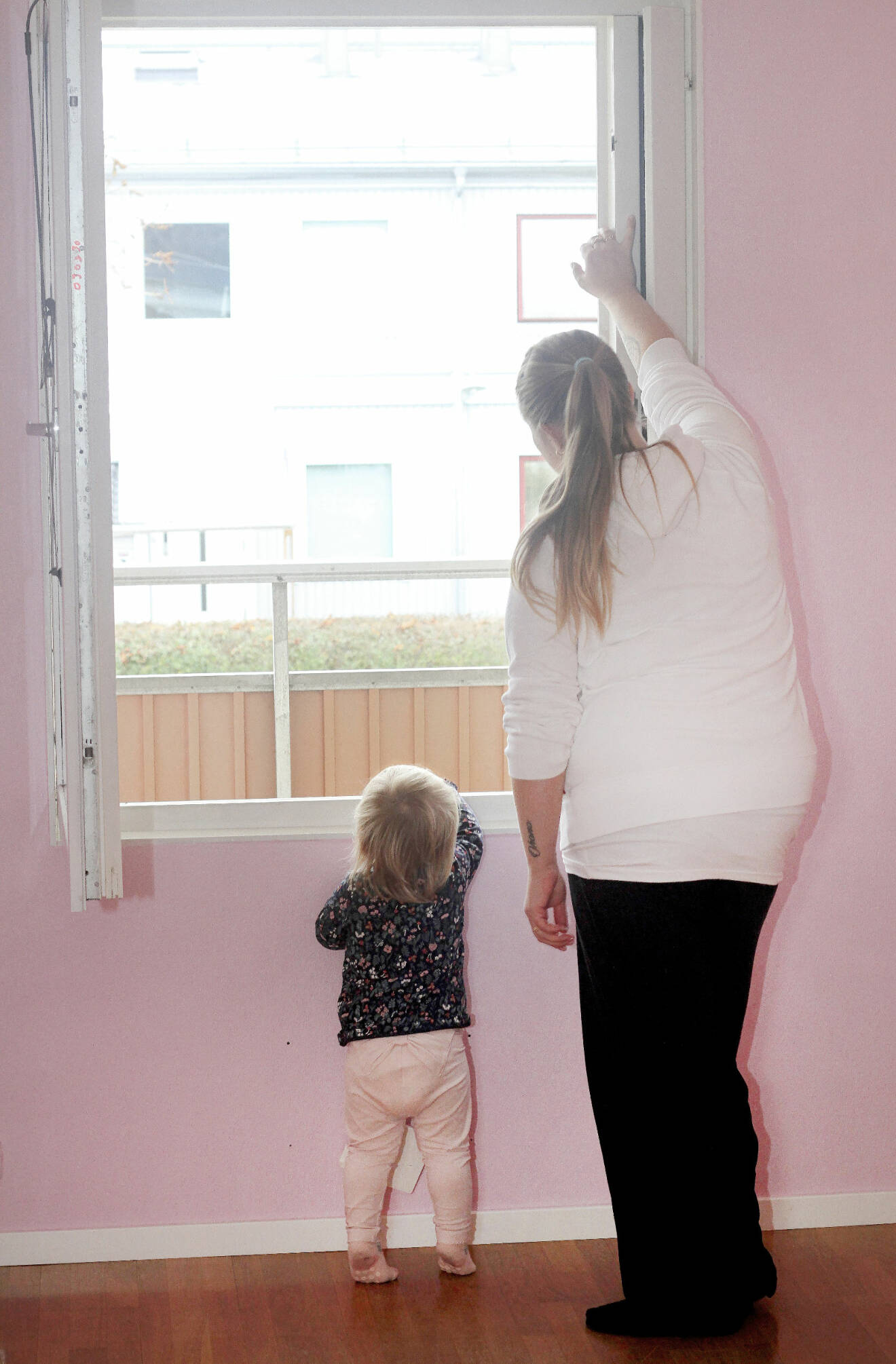 Jennifer och dotter tittar ut genom fönstret på dotterns rum.