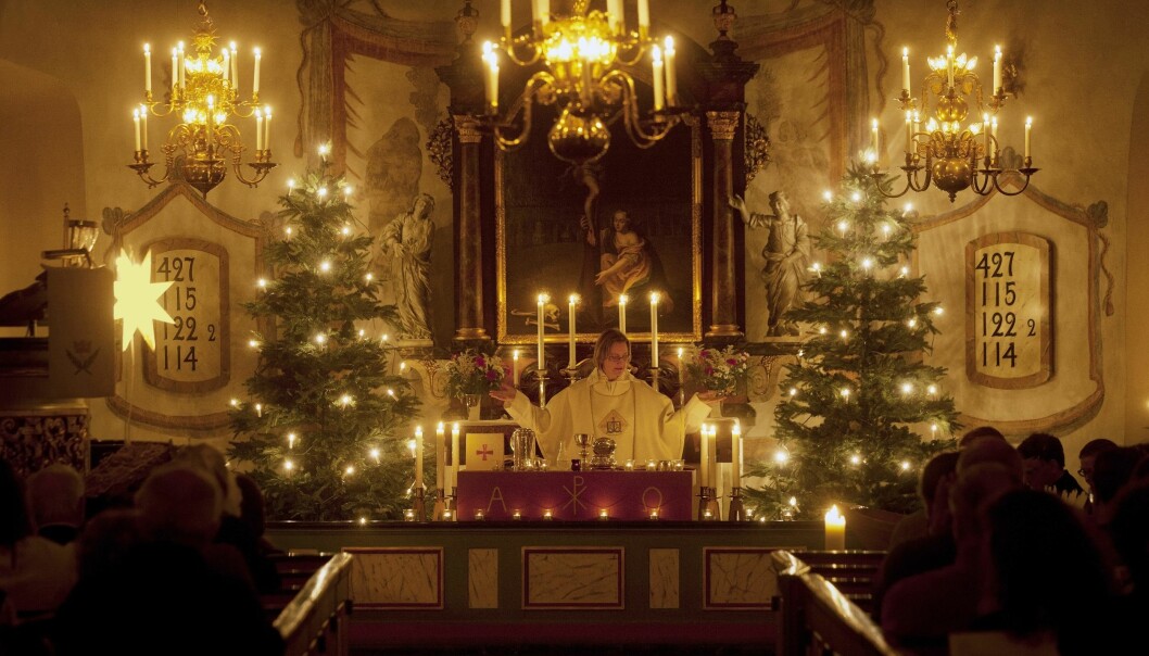 Midnattsmässorna på julafton blev populära. Foto: TT Kvinnlig präst i juldekorerad kyrka.