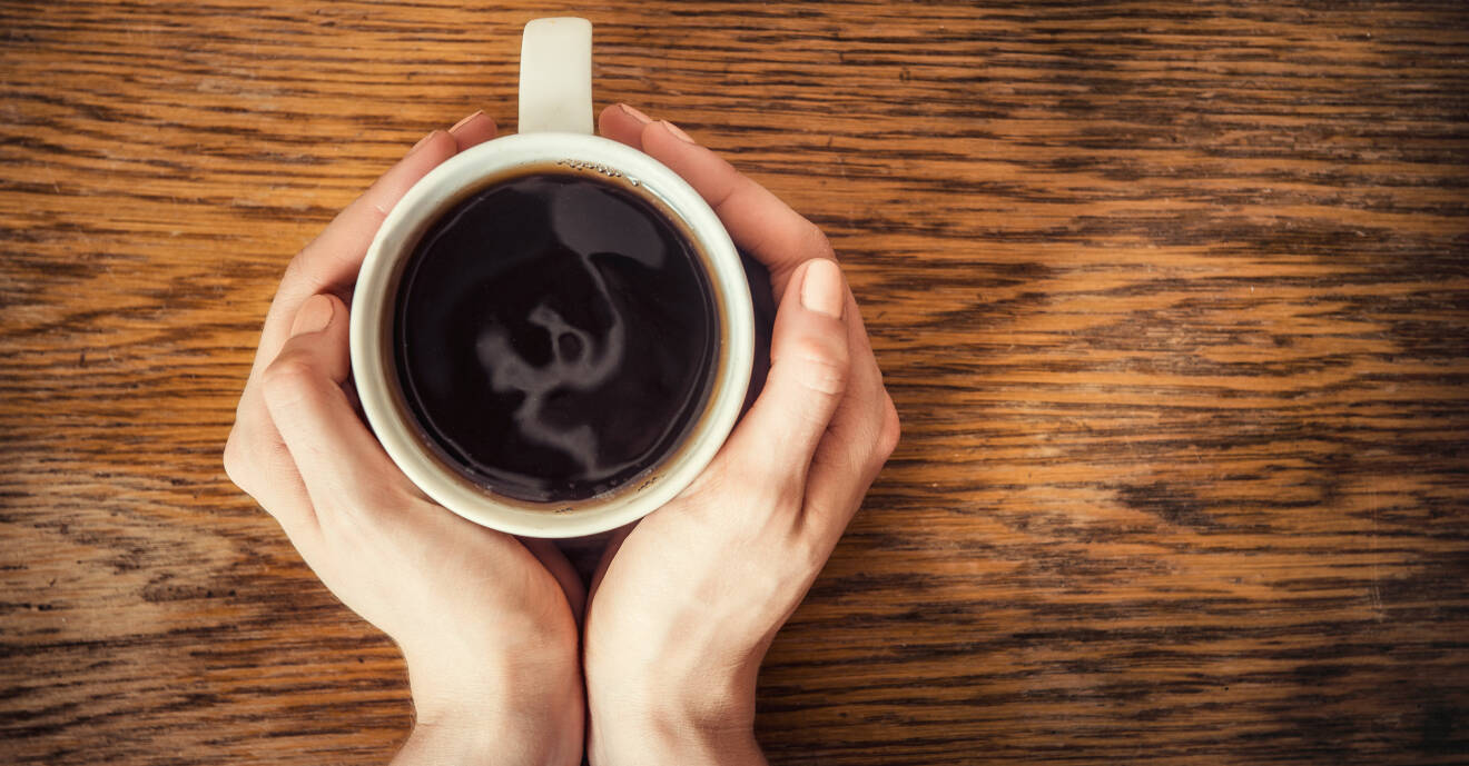 Koffeinabstinens kan utlösa morgonhuvudvärk. Här håller en kvinna händerna runt en kaffekopp.