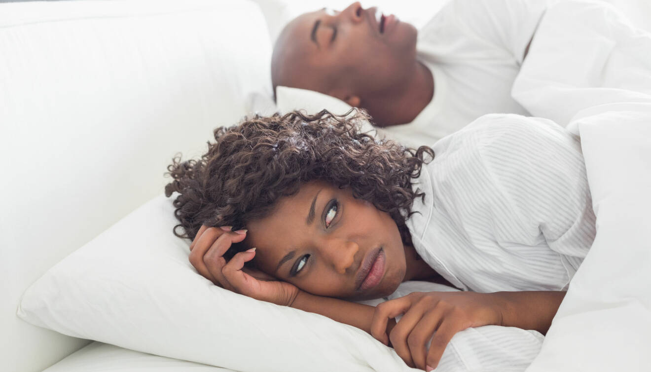 Irriterad kvinna sover med snarkande man.
