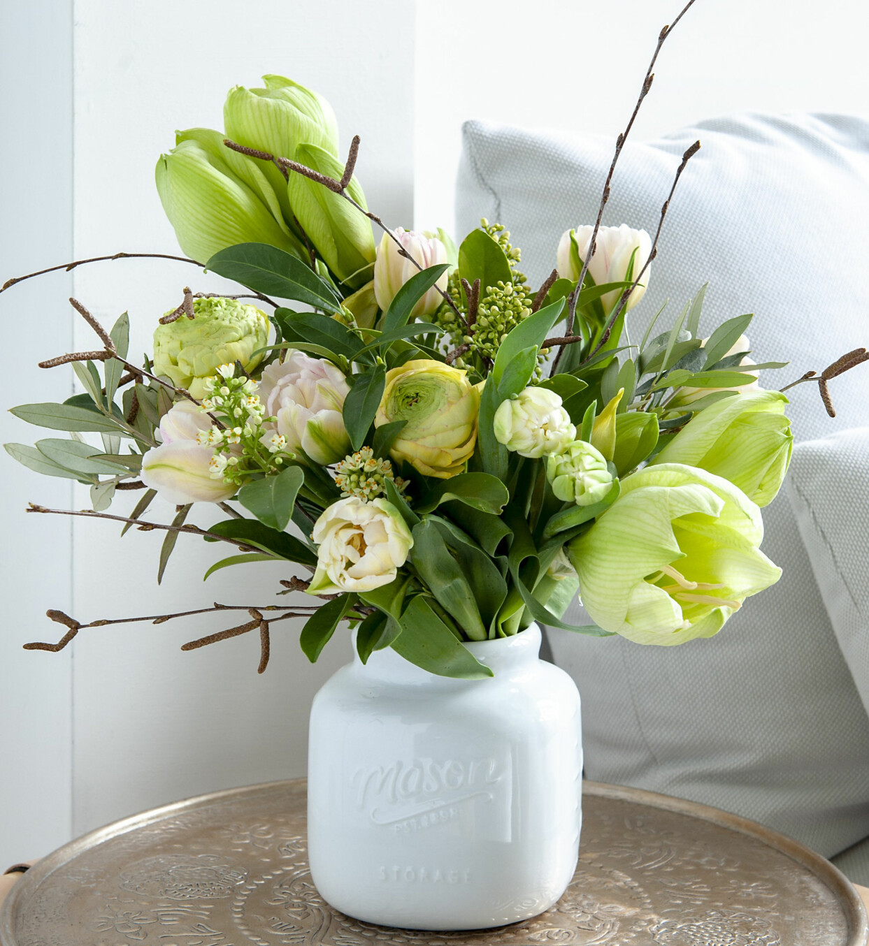 Bukett i gröna och vita toner med tulpaner, amaryllis, kvistar och ranunkler.