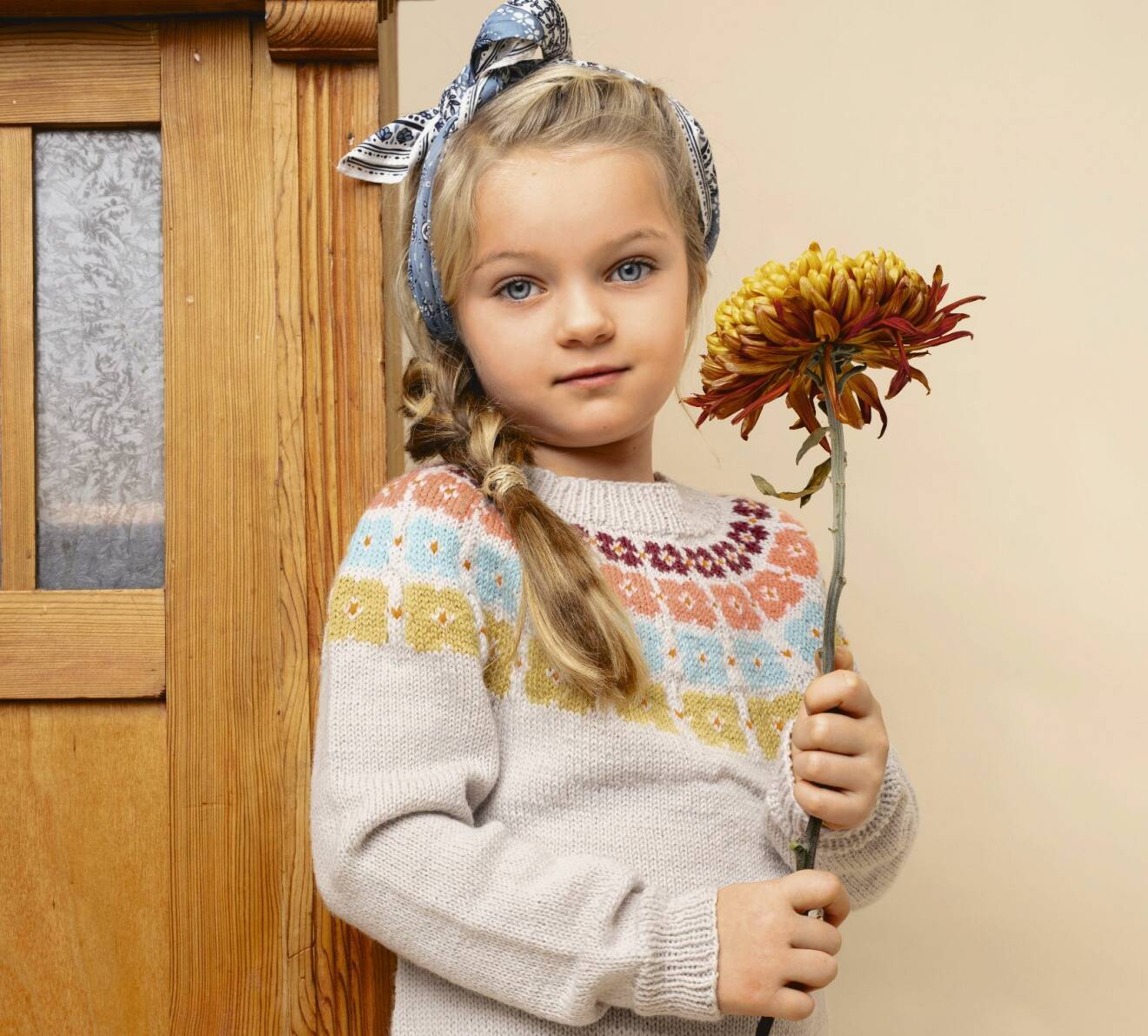 Flicka iklädd stickad barntröja med blommor, från Sandnes.