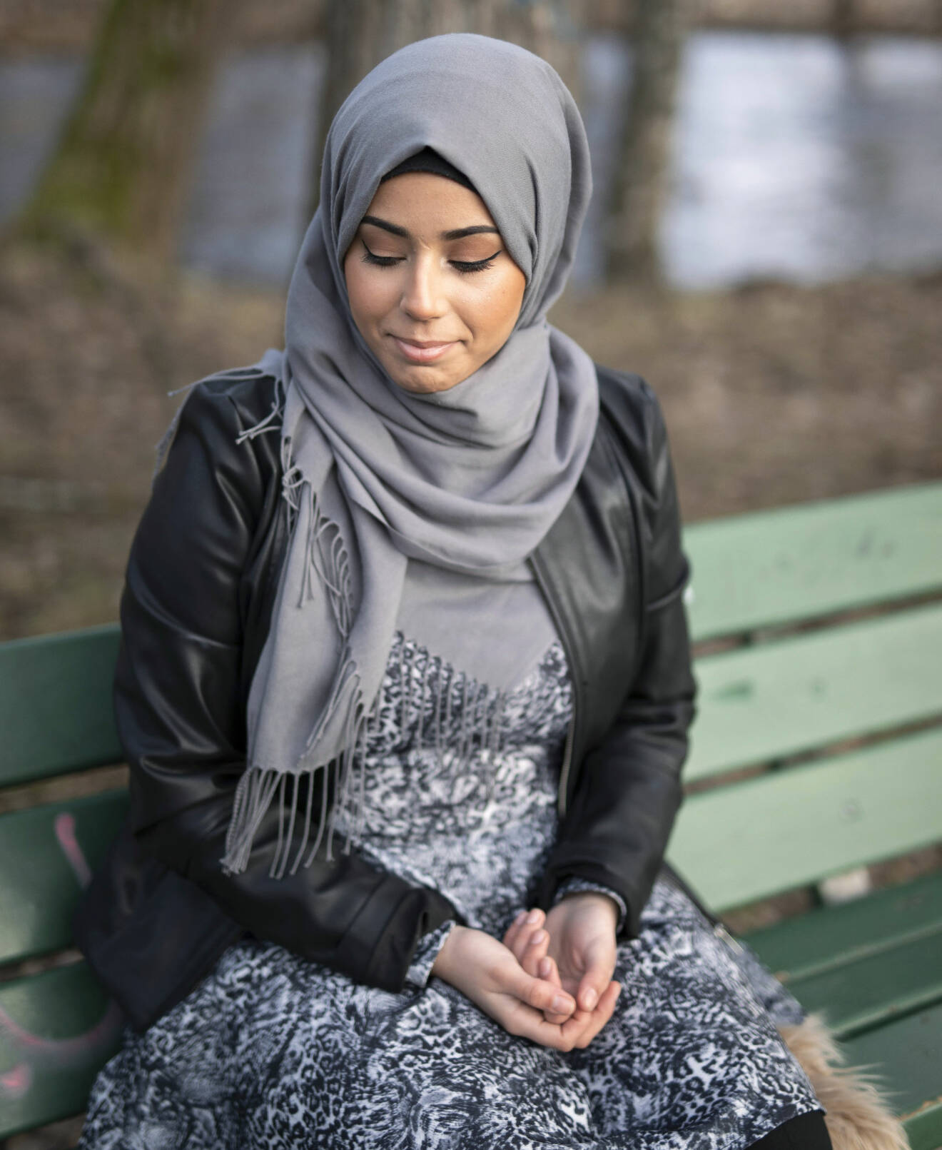 Porträtt av Zahra som sitter på en bänk och berättar om sin tuffa bakgrund.