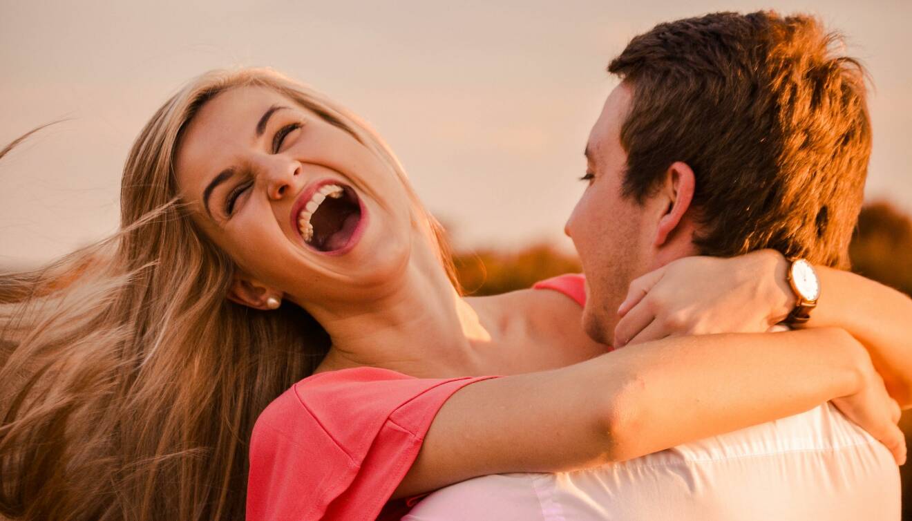 Man och kvinna håller om varandra och skrattar lyckligt.