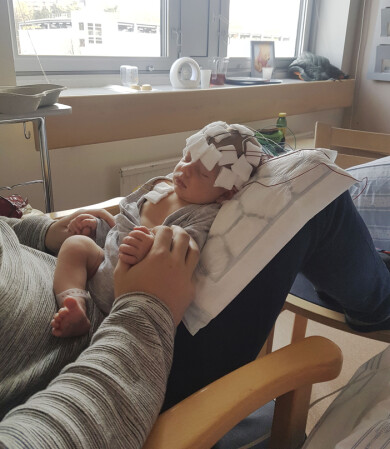 På sjukhuset fick Elton genomgå många undersökningar av hjärnan. Det visade sig att han har Ohtaharas syndrom. Foto: Privat Elton ligger hos pappa Tom med hela huvudet inklätt i slattar och undersökningsutrustning.