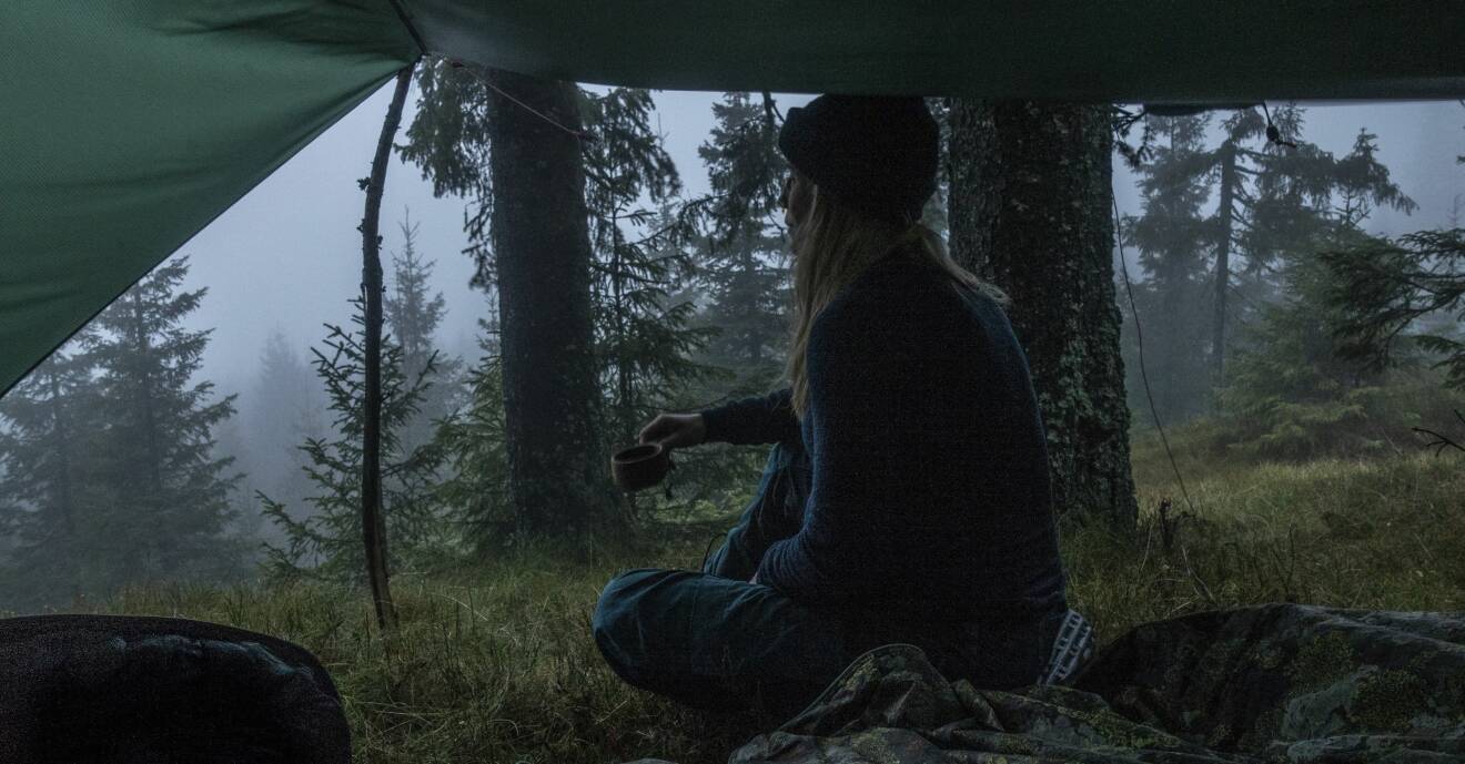 Johanne sitter i ett vindskydd och dricker kaffe i norska Nordmarka.