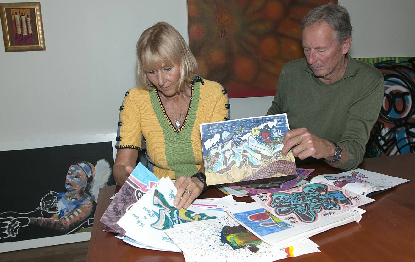 Eva och Jörgen tittar på bilder son sonen Joakim målat.