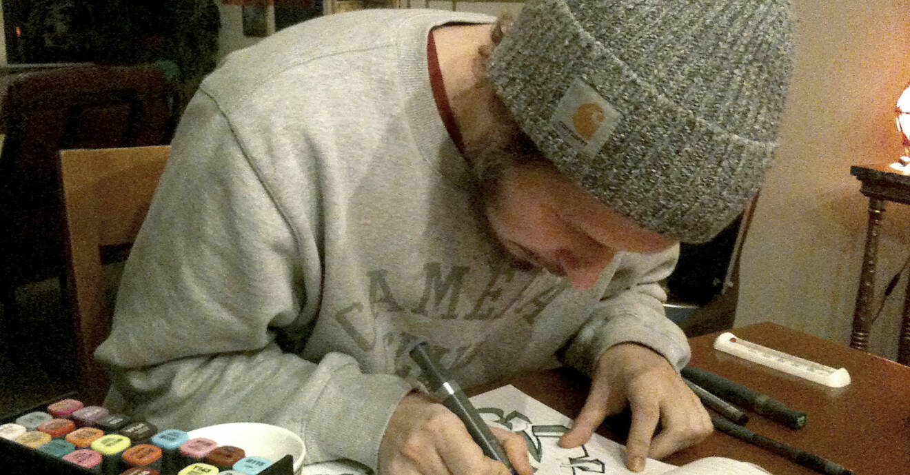 En privat bild av sonen Joakim, som sitter och målar vid ett bord.