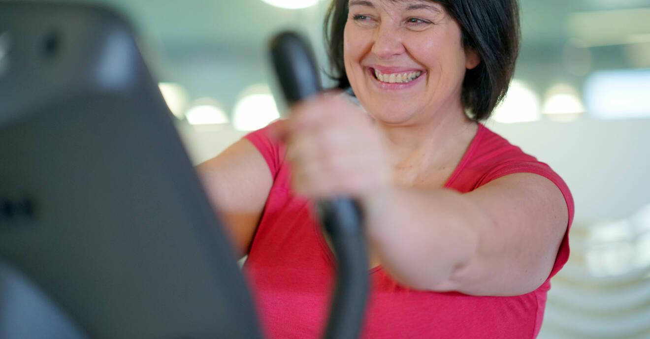 Kvinna sitter på en träningscykel på ett gym.