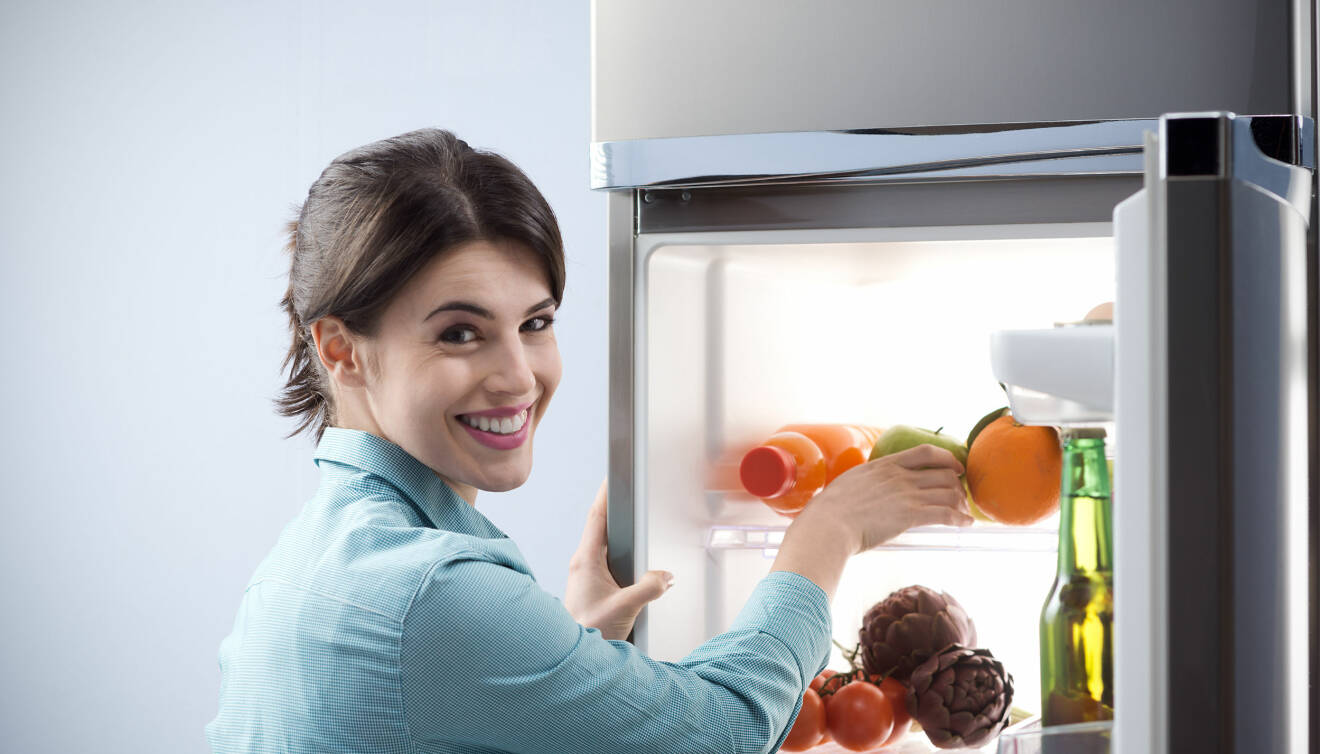 Kvinna som tar mat ur kylskåpet.