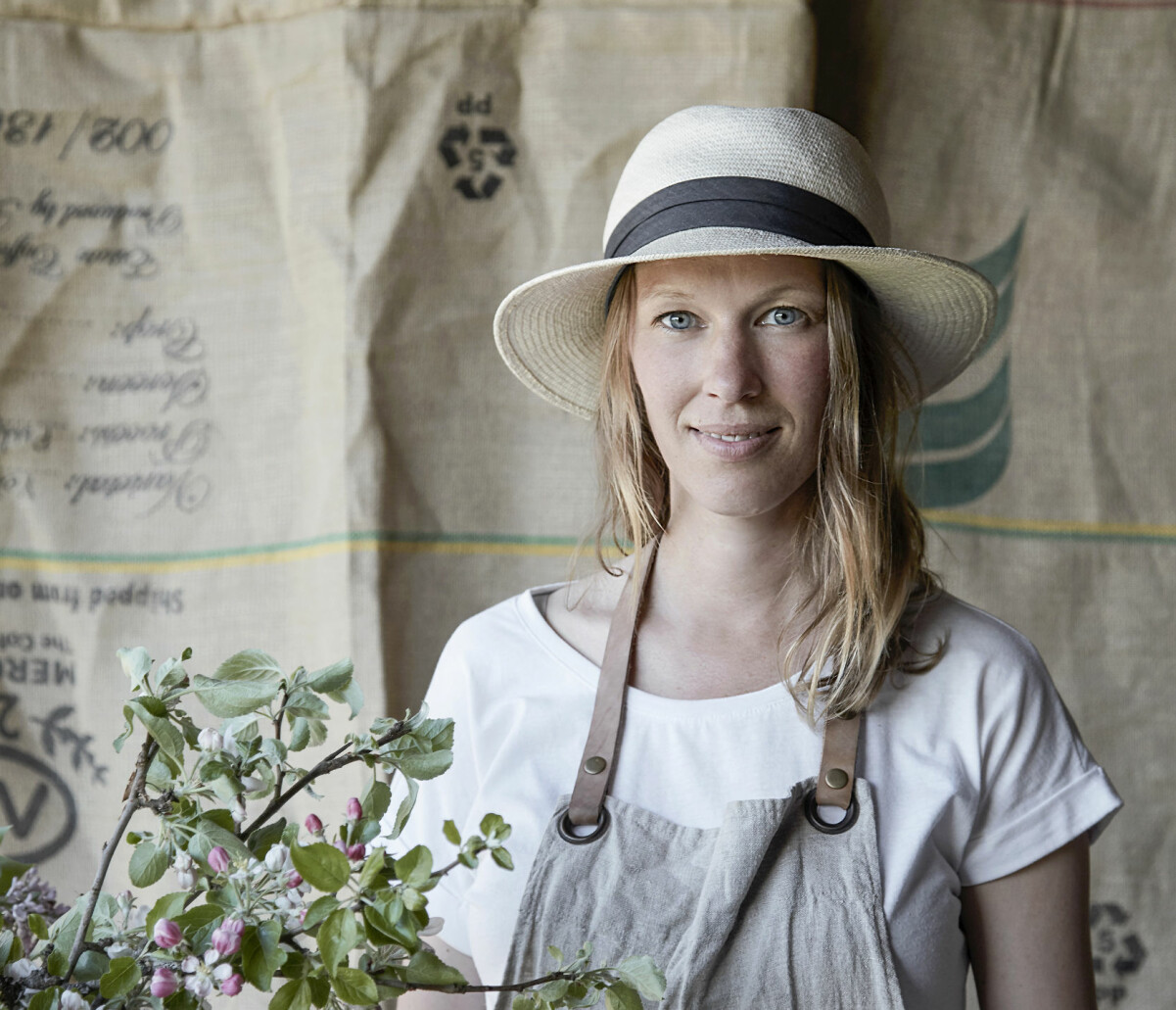 Maja befann sig i en livskris när hon bestämde sig för att flytta från stan och uti skogen. Porträtt av Maja i halmhatt och med en blomma.