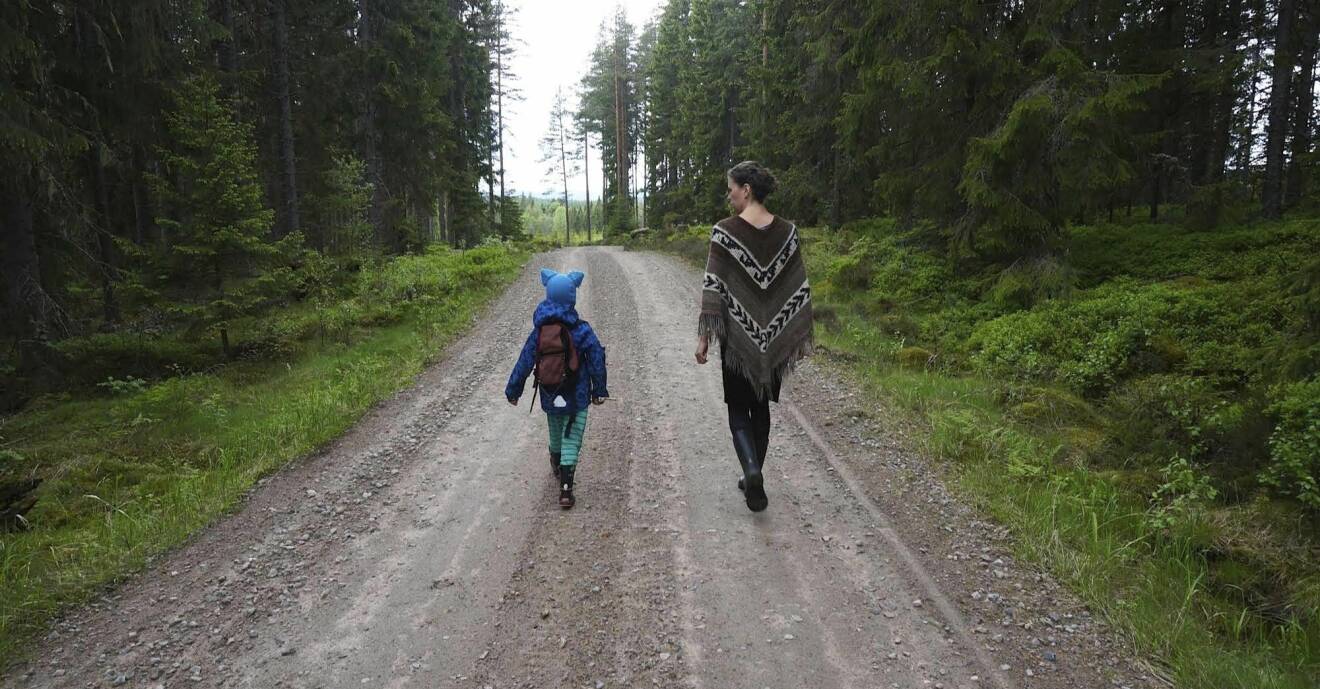 Mor och barn på promenad på en liten skogsväg.