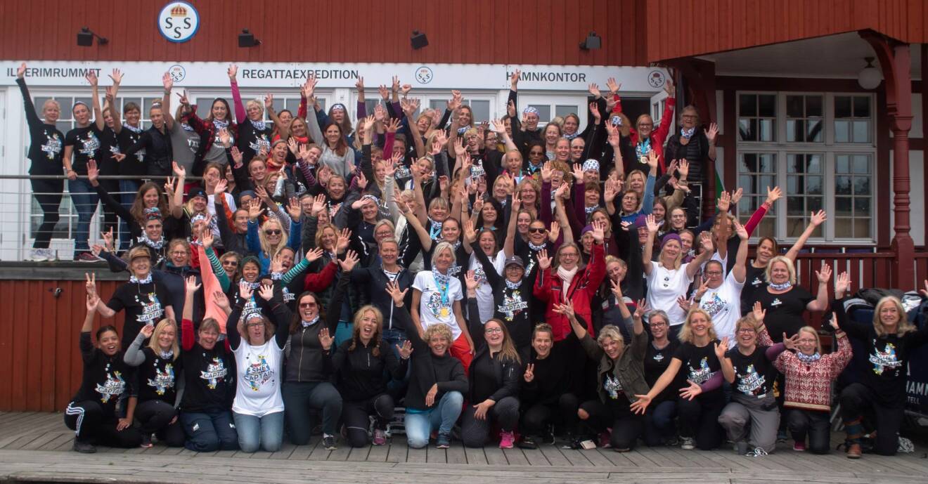 130 kvinnor aktiva i nätverket She Captain framför ett hamnkontor i Stockholms skärgård.