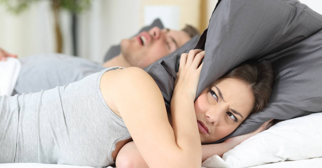 En kvinna försöker sova men mannen som snarkar tvingar henne att ha kudden över huvudet.