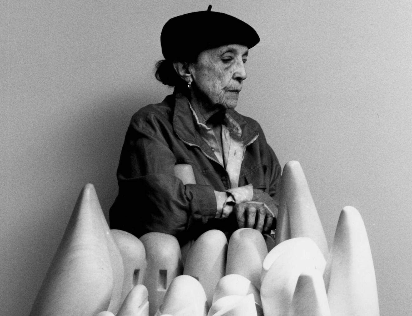 Louise Bourgeois poserar framför en skulptur.