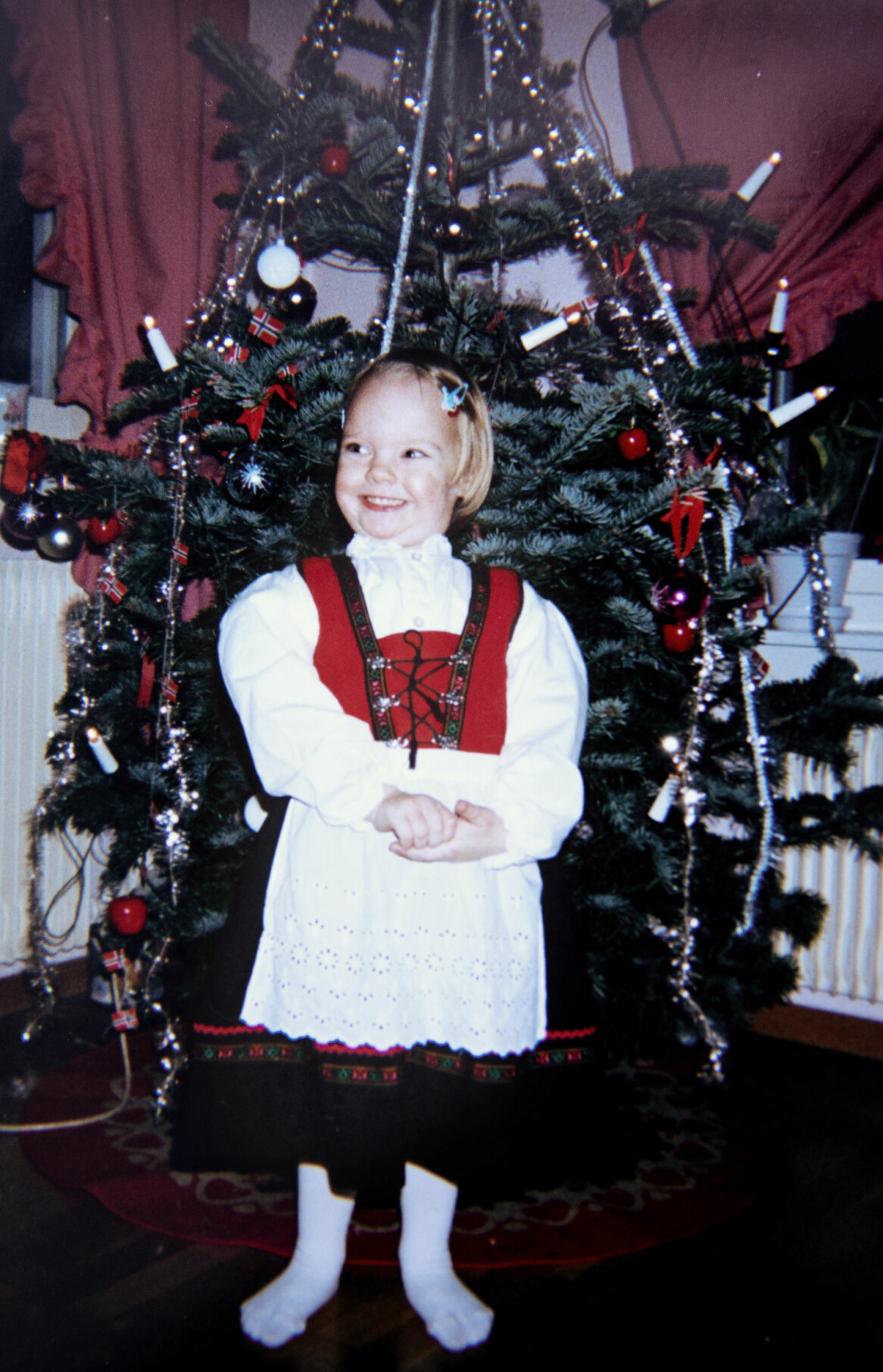En glad liten flicka, ett halvår innan mardrömmen som förändrade hennes liv. Foto: Privat Privatfoto av Benedicte som liten framför familjens julgran.