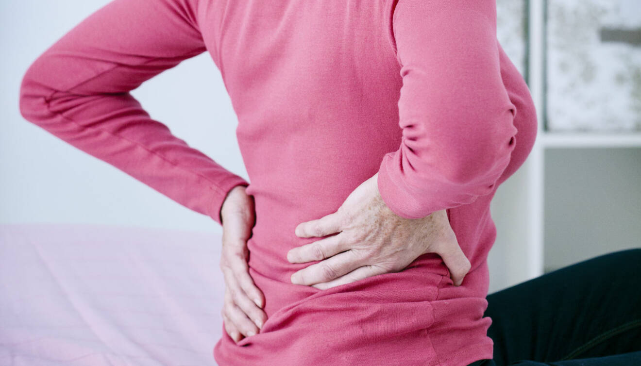Kvinna har smärta i ryggen, troligtvis på grund av dålig hållning.