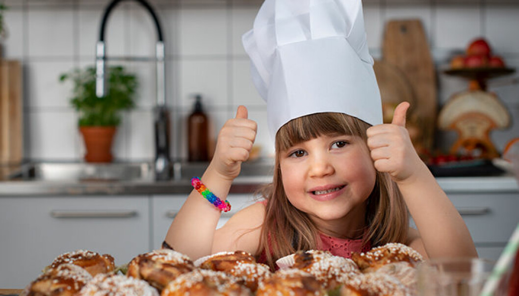 Goda bullar! 4-åriga Ines är stolt över sina hemmagjorda kanelbullar. Flicka gör tummarna upp för sina kanelbullar.
