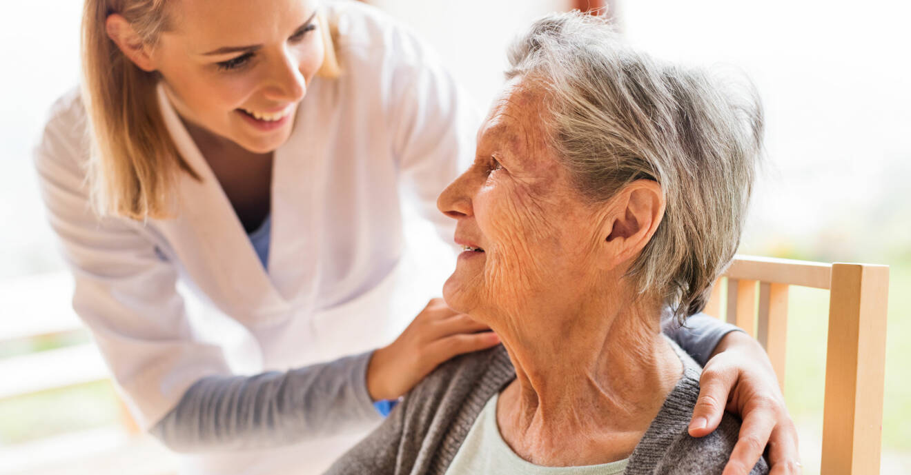 Sköterska tar hand om gammal kvinna på äldreboende.