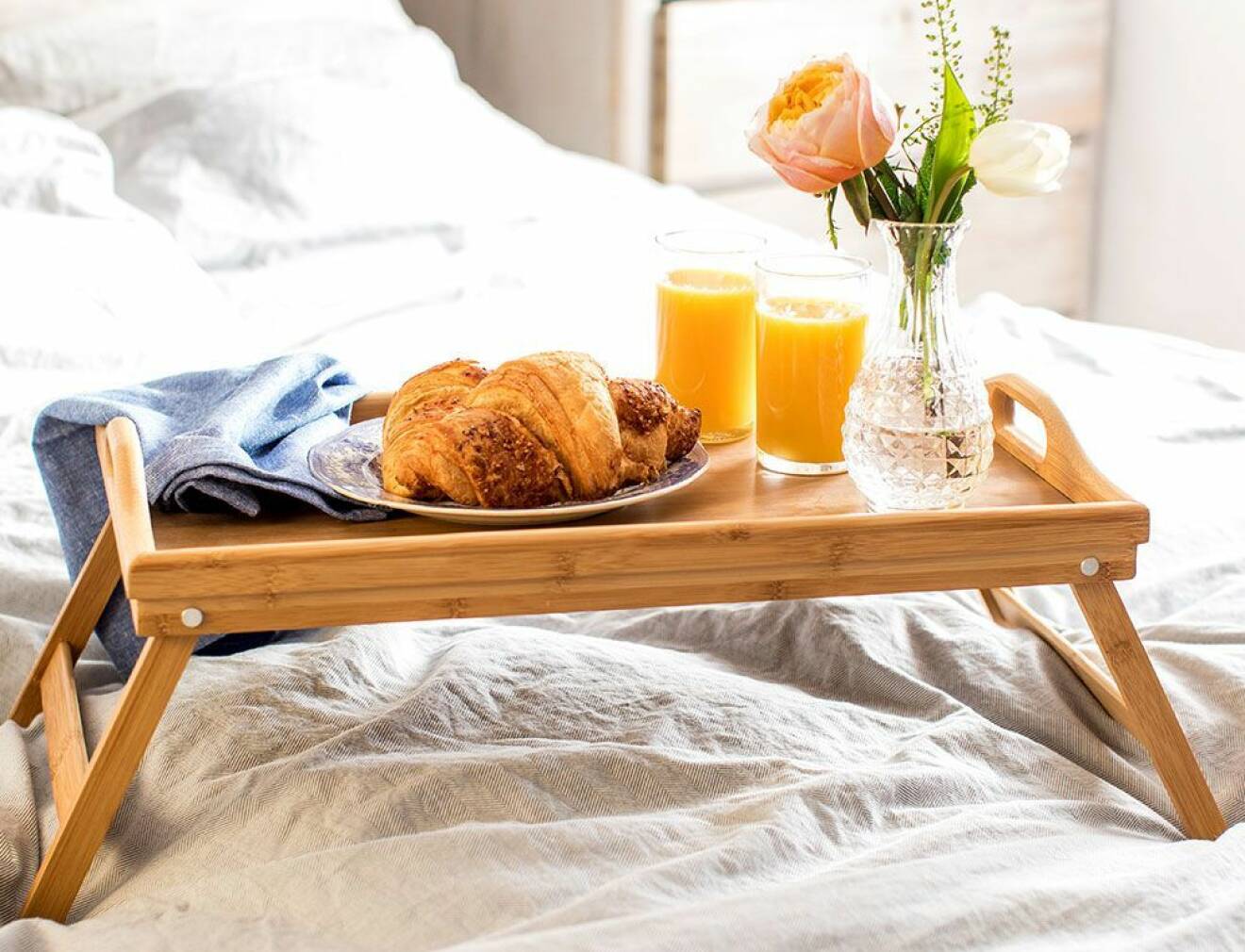 Frukostbricka i trä i en säng.