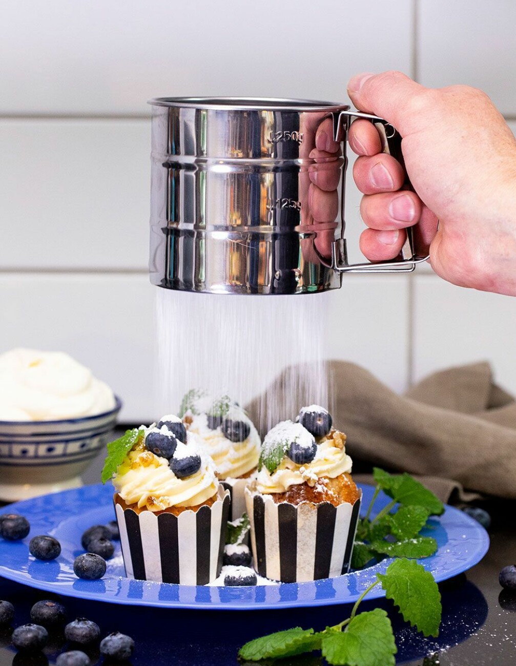 Mjölsikt siktar florsocker på muffins.
