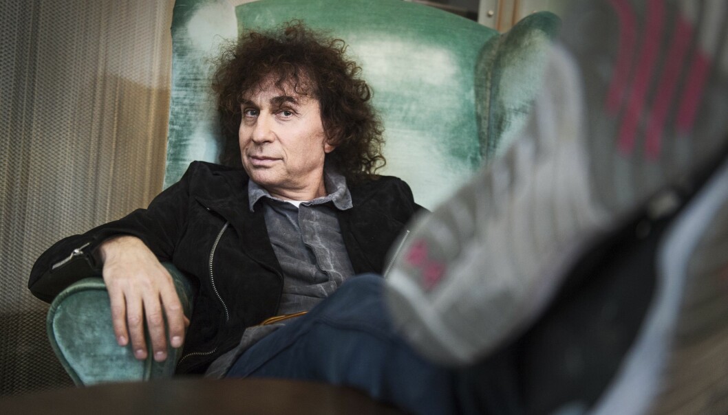 Magnus Ugglas släppte sin första skiva för 45 år sedan. Foto: Christian Johansson/TT Artisten Magnus Uggla sitter bekvämt tillbakalutad i en fåtölj.
