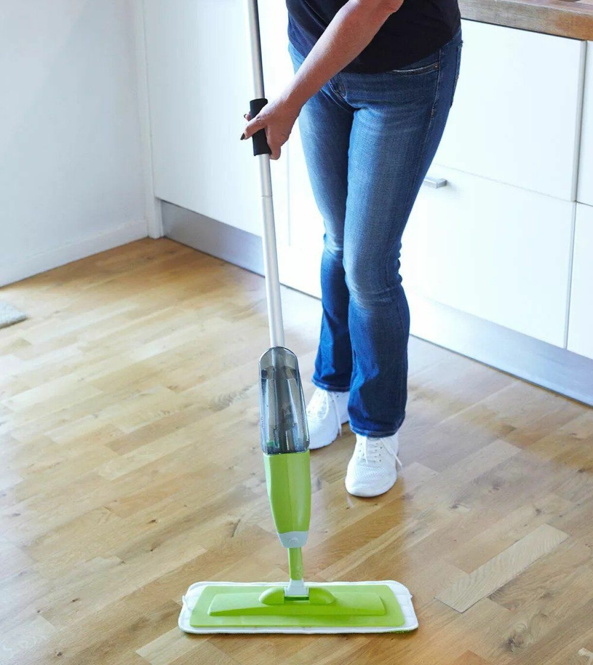 Kvinna städar med mikrofiberduk på spraymopp.