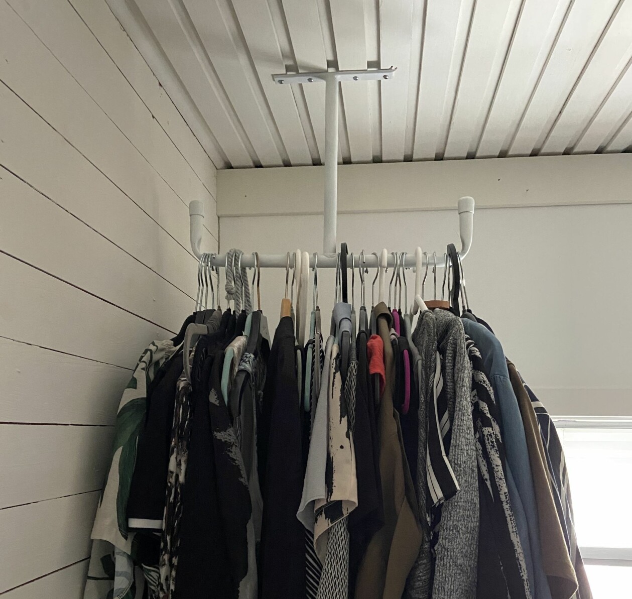 En redskapskrok som vanligtvis hänger i garage och förråd fick lite färg och blev en klädhängare. Foto: Privat En klädhängare i taket och kläder på galgar.