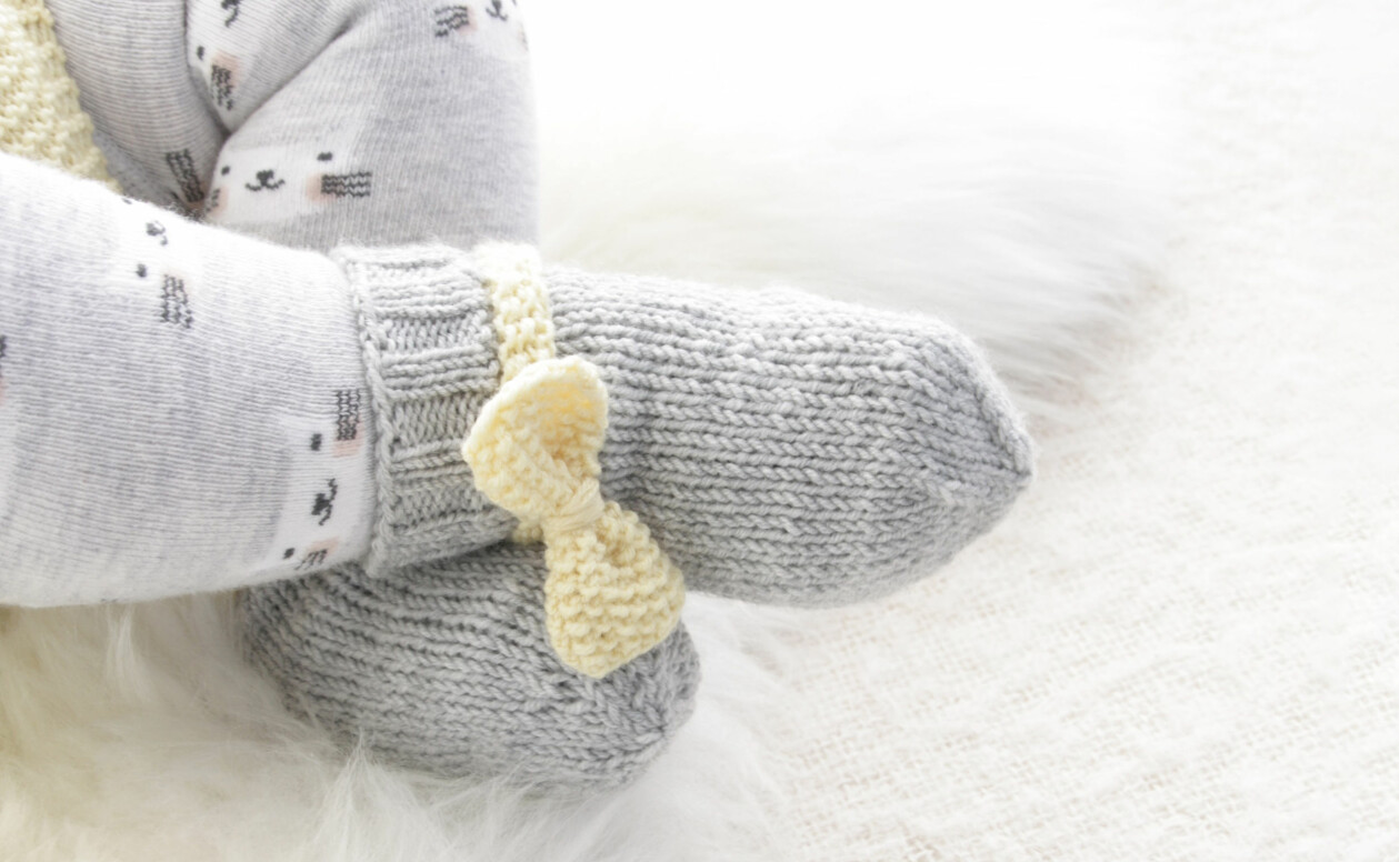 Mjuka sockor i merinoull med en söt rosett. En perfekt present till nyblivna föräldrar! Mosstickade sockor till baby från Drops Design