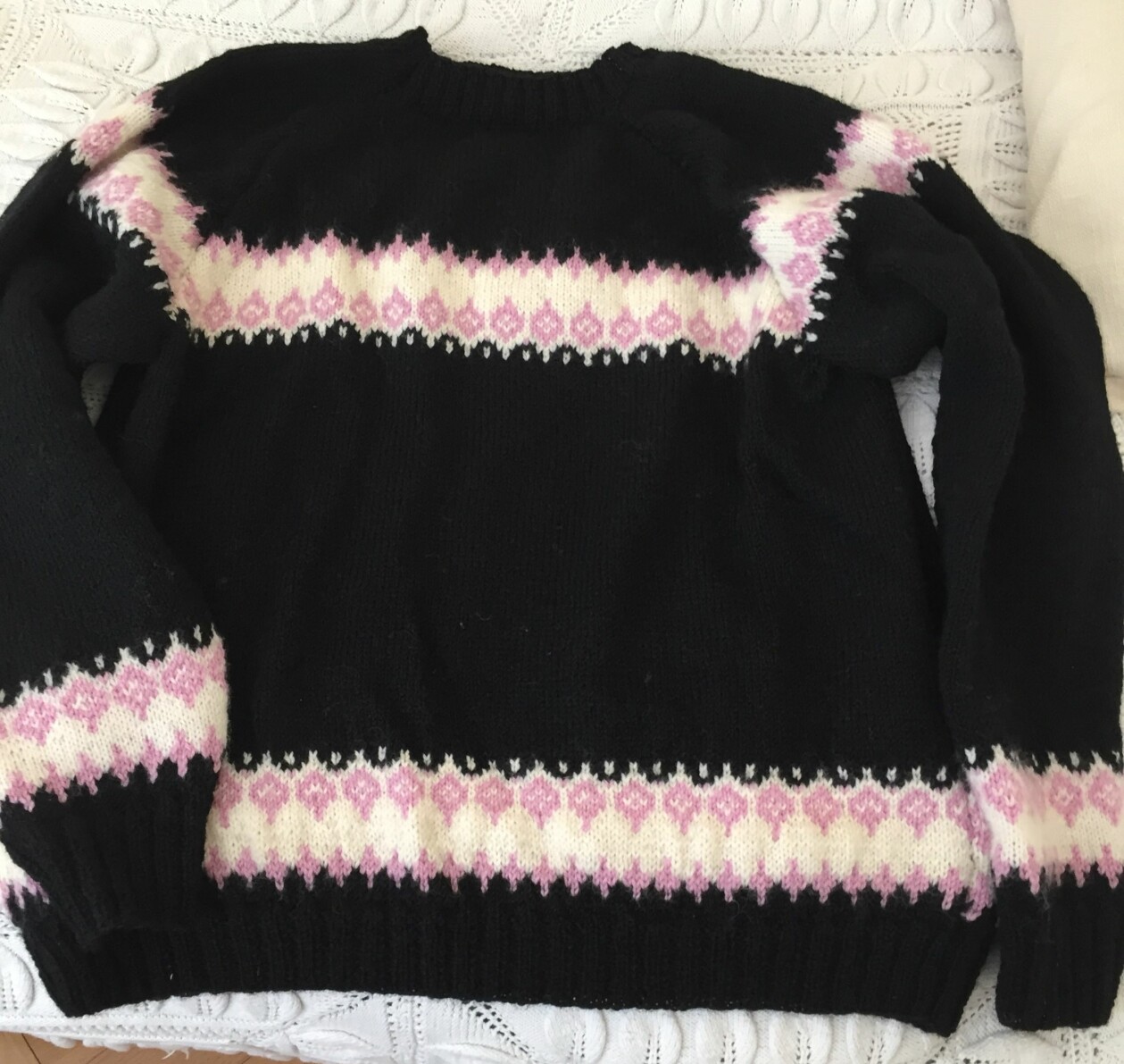 Helen sparade 1400 kronor på att sticka en kopia av tröjan hon hittat i butik! Foto: Privat En stickad svart tröja med vitt och rosa mönster.