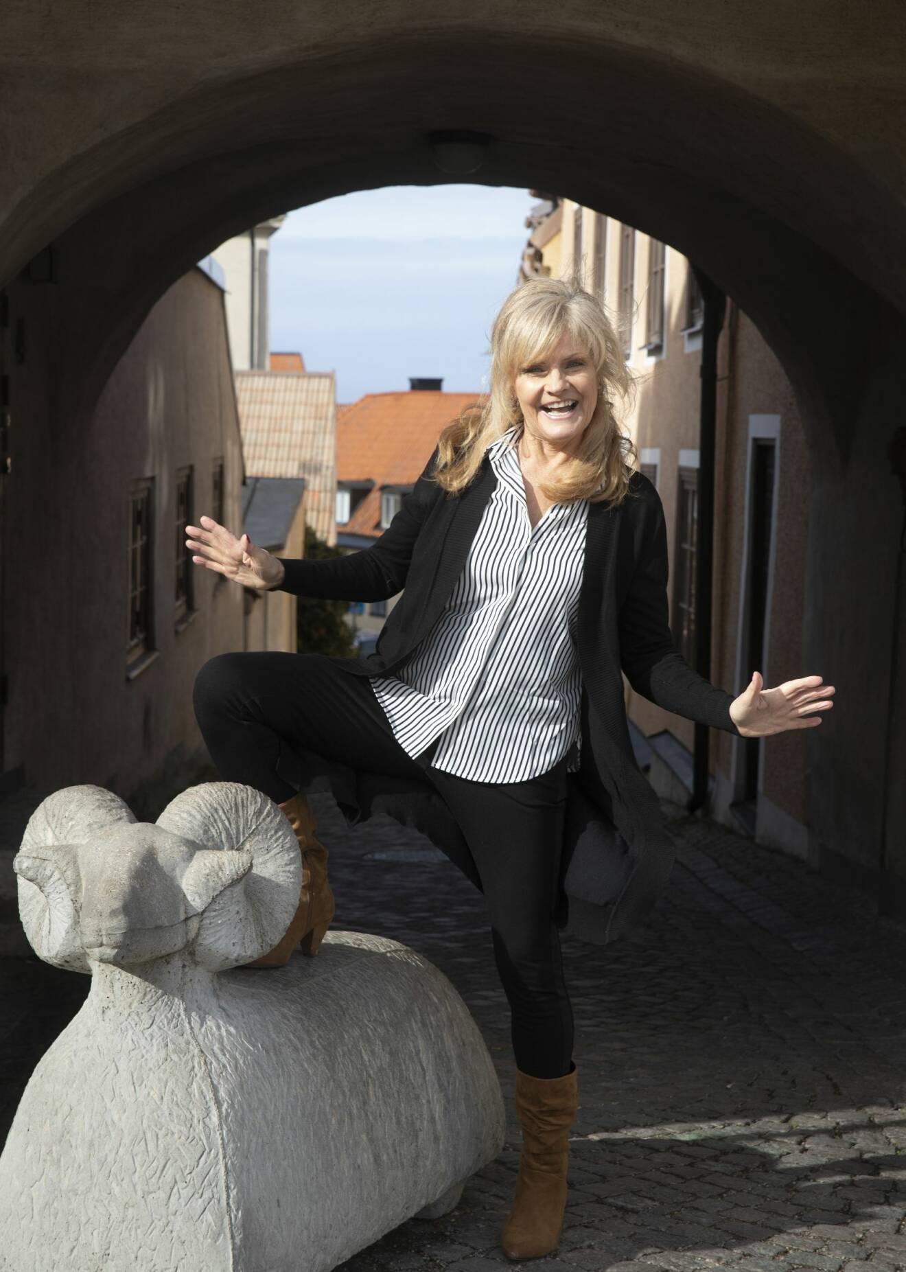 Pia poserar glatt vid ett av Visby-fåren i betong.