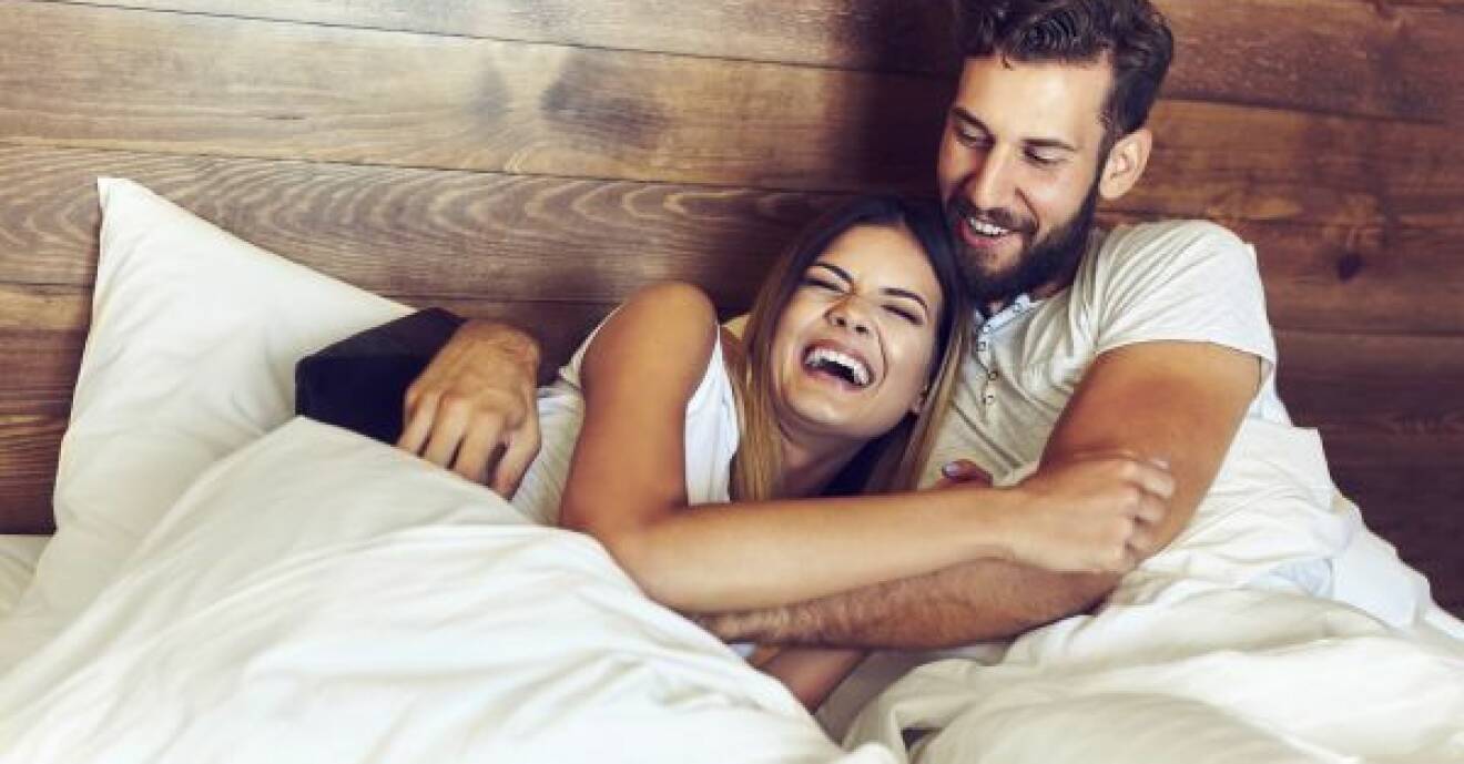 Man och kvinna skrattar och kramas i säng.
