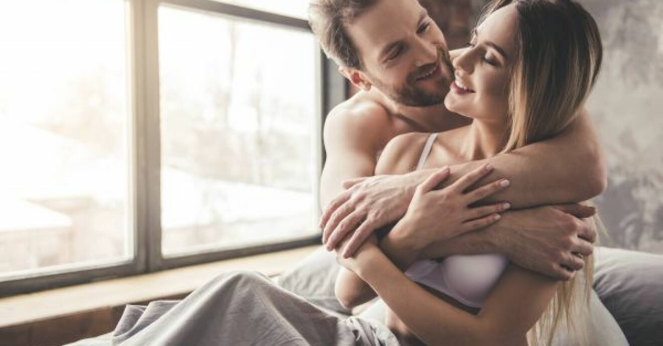 En man och en kvinna kramar om varandra, sittandes i säng.