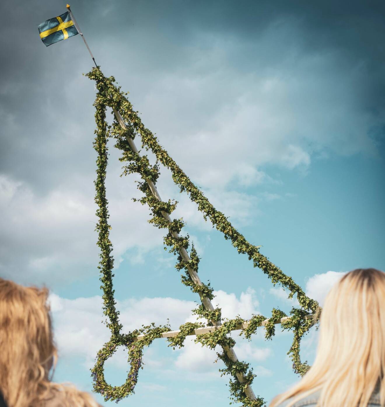 En midsommarstång med en svensk flagga i toppen.