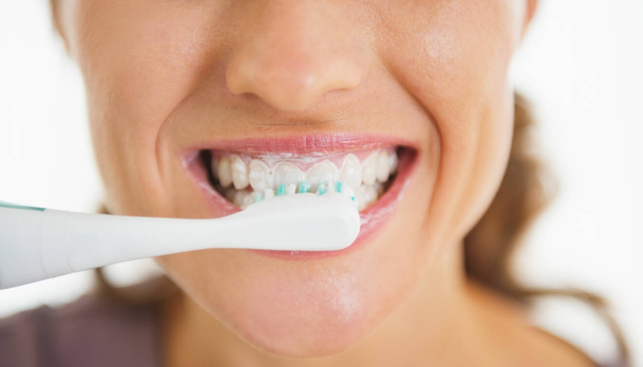 Kvinna borstar tänderna med tandborste.